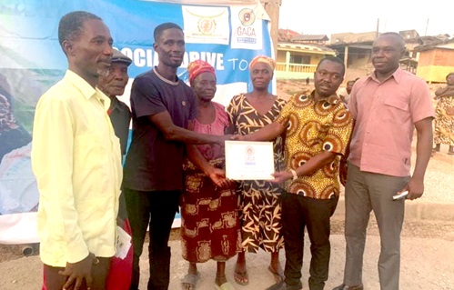 The acting Central Regional director of the CNC, Ebenezer Nti, presenting a certificate of commitment to ending child marriage to the assembly member for Ekon, John Mensah. With them are some community leaders