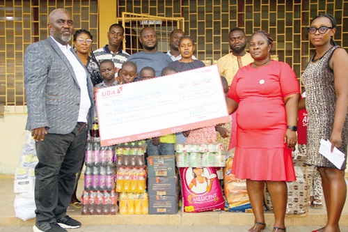 Kunle Olutimehin (left), Country Manager, Marketing Support Consultancy Limited, presenting a dummy cheque and the items to Janet Owusu (2nd from right), a social worker at the orphanage