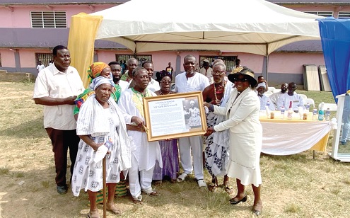  Rev. Rebecca Frederica Akweley Abladey (right) presenting the citation to Eric Kingsley Nortey Dowuona, son of Nii Narh Dowuona II, the Chief of Boi. With them are children and family members of the late Chief