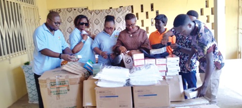 Benjamin Ekow Otoo (left), President, Mfantseman Kroye Kuw, some association members, Catherine Ampah-Brient (3rd from right), Ekumfi District Director of Health, and GHS staff inspecting the items