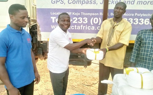 Gyekwe Twum Ampofo (middle), Procurement Manager of CCT, and Samuel Tulasi (left), Warehouse Officer of the company, presenting the items to one of the fishermen