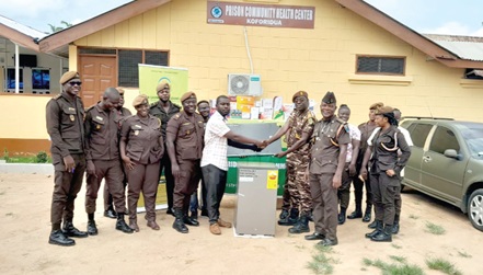 Godson Adzafi (left), Koforidua Area Manager of ASA Savings and Loans Limited, presenting one of the items to Chief Superintendent Francis Agyeiri Kwakye (2nd from right), Officer in charge of the Koforidua Prisons
