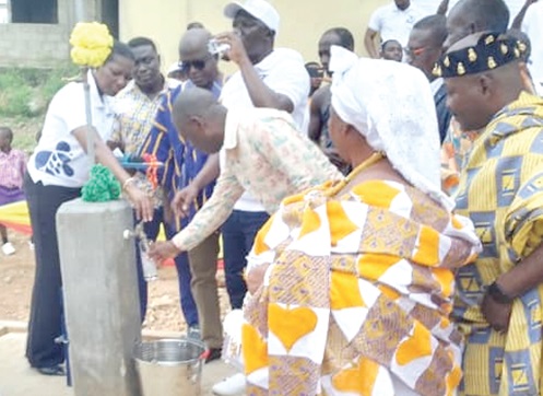 Aloysius Adjetey (in cap), the Chief Executive Officer of CWSA, taking a drink after commissioning the water facility at Odonase. With him are other dignitaries present at the ceremony 