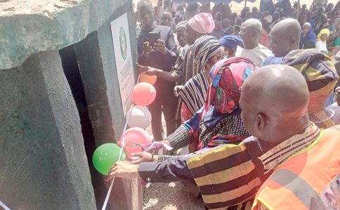 Baba Gana Wakil (arrowed), Resident Representative of ECOWAS, being supported by Abdallah Salifu (right), Northern Regional NADMO Director, to cut the tape to commission the water facility