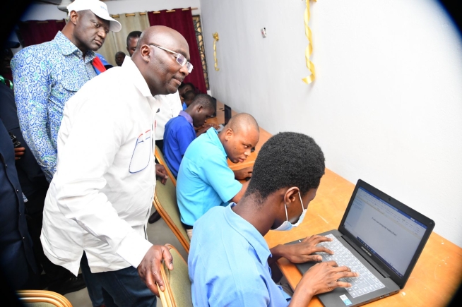 Dr Mahawudu Bawumia (left) looking on while some students try their hands on the laptops presented