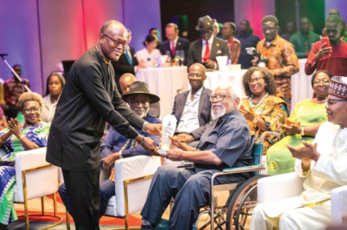 Isaac Okpoti Adjei (standing), the acting General Manager of Movenpick Ambassador Hotel, handing over an award to Ambassador Richard Maximilan Akwei (seated), one of the awardees, while Dr Mohammed Ibn Chambas (seated right) and others watched on