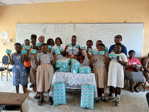 Gifty Owusu-Boakye (middle), President of the Ladies Club of Koforidua Taxpayer Service Centre of the GRA, her colleagues and pupils of Old Asuoya M/A Junior High School displaying the sanitary pads