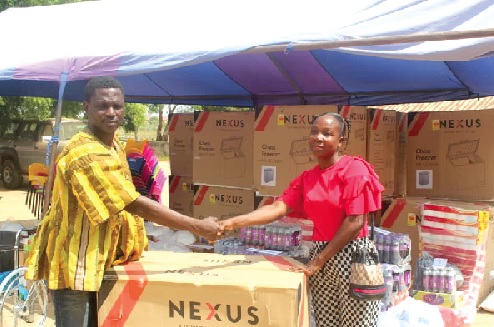 Sampson Tetteh Kpankpah, District Chief Executive for Ada West, presenting an item to one of the beneficiaries