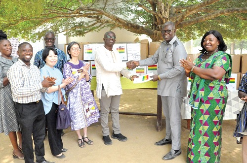 Frederick Birikorang (3rd from right), Director of Partnerships and Affiliations, GES, presenting a book to Francis Agbemadi (2nd from right) while Isabella Ayimey (right), North Tongu District Director of Education, and officials of JICA look on