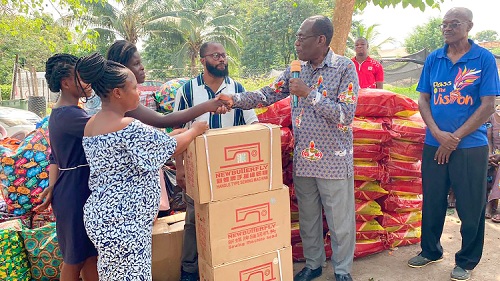 Ebenezer Sedufia (right), Vice-President of the Full Gospel Business Men Fellowship, handing over the sewing machines to some of the beneficiaries