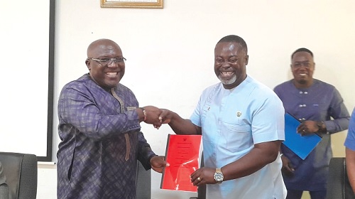 Seth Kwame Acheampong (left), Eastern Regional Minister, presenting the 2024 Performance Contract to Isaac Appaw-Gyasi, New Juaben South Municipal Chief Executive