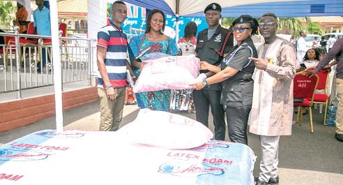 Gifty Appiah (2nd from left), PRO, Latex Foam, handing over the items to Under Cadet Sgt. Emmanuel Azure (middle), being supported by C. Supt. Rosina A. D. Gariba, an officer at the National Police Training School in Accra. With them are other officials of Latex Foam