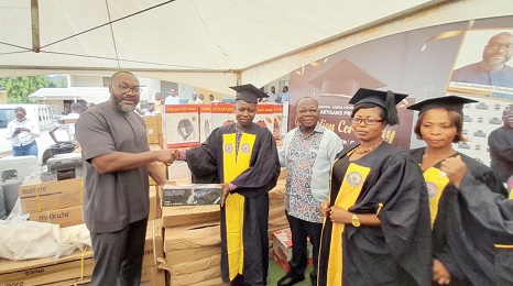 Opoku Awenee Danquah (left), Chief Executive Officer of GNPC, presenting one of the items to Emmanuel Kwaming from Adawso. Looking on are Freddie Blay, the Board Chairman of GNPC, and other graduands