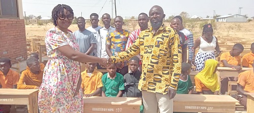 Alice Atubiga (left) presenting the desks to Ayinga Abagre Yakubu (right), DCE for Binduri