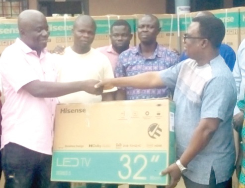Simon Kweku Tetteh (left), the Lower Manya Krobo Municipal Chief Executive, presenting a television set to Samuel Kwesi Tettey (right), the Municipal Director of Education