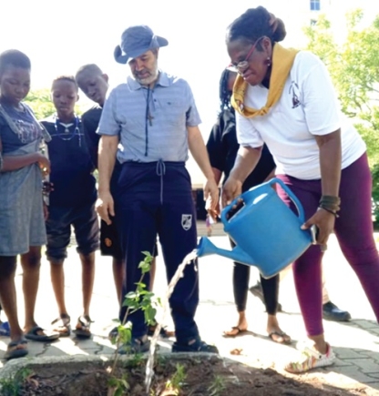 Dr Emefa Takyi-Amoako (with watering can), Vice-President  of the OLA Sacred Heart Confraternity, watering a plant, while Rev. Fr Francisco Machado, Parish Priest of the Our Lady of Assumption Parish, and some of the Tarcisians  look 