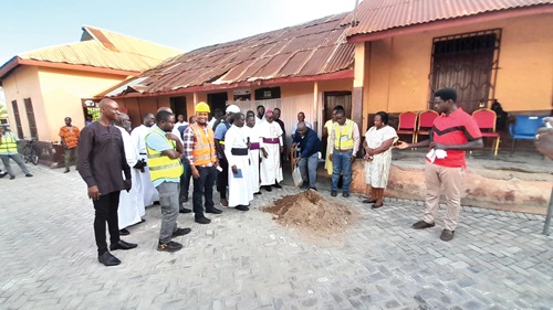 Michael Okyere Baafi (with shovel), MP for New Juaben South Constituency, cuts the sod for construction work to begin. Looking on are Rt. Rev. Felix Annancy (4th from left), Bishop of the Koforidua Diocese of the Anglican Church, the contractors and consultant