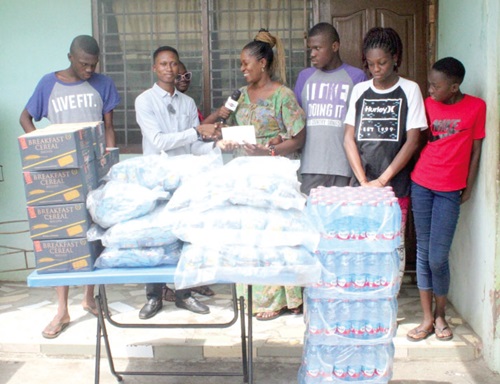 Gideon Teye (2nd from left) presenting the items and cash on behalf of Twellium Industrial Company Limited to Diana Ayivor (3rd from left), the mother of the autistic twins
