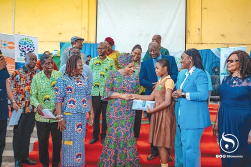 Samira Bawumia presenting a pack of sanitary pads to a pupil
