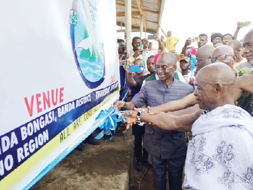 Johnson Asiedu Nketiah (left), National Chairman of the NDC, being assisted by Nana Bankwade (right), Osiakwanhene of the Banda Traditional Council, to cut the tape to inaugurate the project
