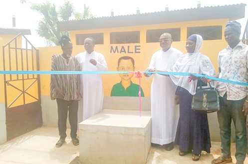 Rev Fr. Sebastian Zaato (middle), Coordinator of TADO, being supported by Alhassan Ramatu (2nd from right), District School Health Coordinator for Kumbungu, and some community  elders to inaugurate one of the facilities at Voggu R/C Primary School