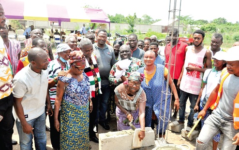 Atsufe Sewordor, the Kpetoe Market Queen, laying a block to signify the commencement of the project while Charles Agbeve (behind the market queen), MP for the area, and other dignitaries and guests look on