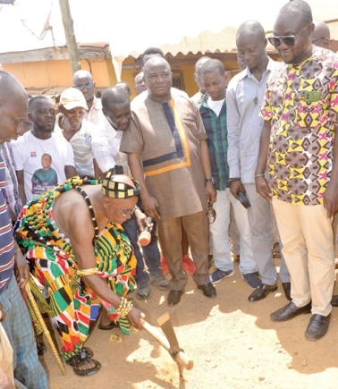 Nana Ampomah Kubrah Yeboah (with pickaxe in hand), Akyem Aboabohene, cutting the sod for the commencement of the road project