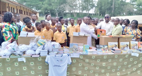 Rev. Fr Neyoh presenting the books on behalf of Asare-Afiyie to Michael Kudzo, head teacher of the school