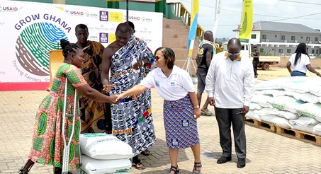Theresah Randolph (2nd from right), Country Manager of YARA Ghana, being assisted by Nana Twumasi Dankwa (middle), Gyaasehene of the New Juaben Traditional Area, to present a bag of fertiliser to Grace Odi, one of the beneficiaries