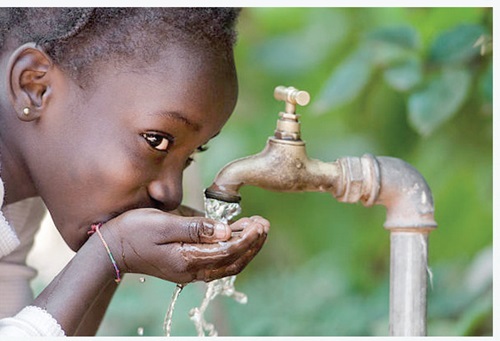A girl drinking water from a tap