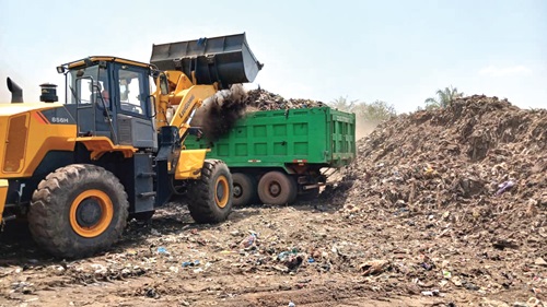 A payloader collecting the age-old rubbish heap into a truck