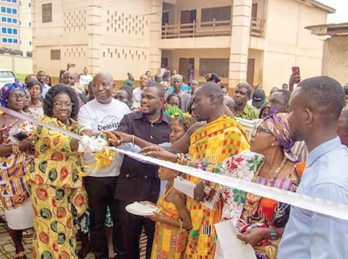 Dr Eric Nkansah (arrowed) being assisted to cut the tape to officially inaugurate the library
