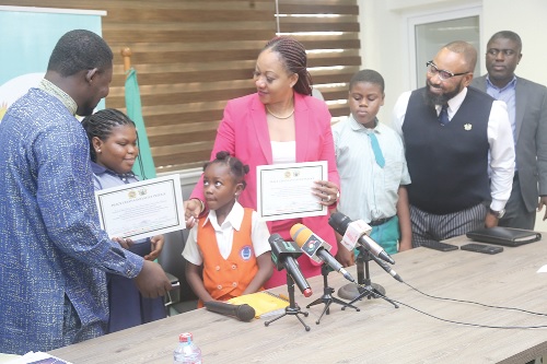 Jean Mensa (middle), Chairperson of Electoral Commission, and Obenfo Nana Kwasi Gyetuah (left), National Executive Director, Ghana National Council of Private Schools, displaying a peace message after signing with the school children at the office of the Electoral Commission. Picture: SAMUEL TEI ADANO