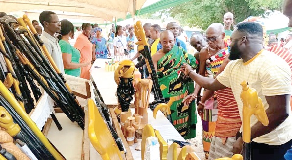 A beneficiary and exhibitor explaining a point to some dignitaries at his stands 