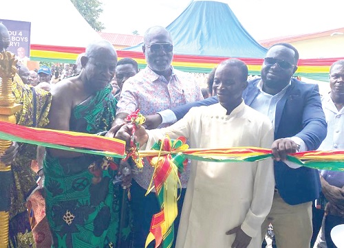 Alex Incoom, DCE, being assisted by George Aboagye, MP, and Obrempong Sintim Poku III, Mansohene, to cut the tape for the inauguration of the new school block