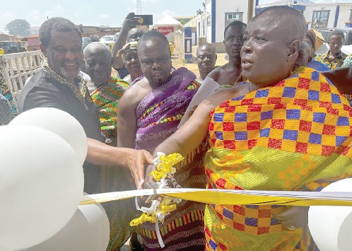Robert Kuzoe (left), Head of MTN Ghana Foundation, being assisted by Nana Boakye Yiadom, Wiamoasehene, to cut the tape to open the library. INSET: Some students trying their hands on the computers