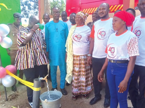 Cletus Azaabi (left), Board Chairman of the bank, having a taste of the water after commissioning of the borehole at the Ghana National Fire Service in Pusiga