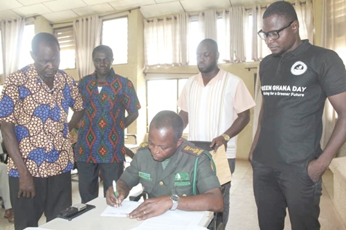 Jonathan Obour Wiredu, Deputy Bono East Regional Director of the Forestry Commission, signing the agreement. With him are the parties involved 