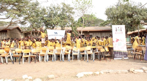 Some of the schoolchildren displaying the tables and chairs donated to them