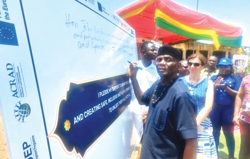 John Kudzo Gyapong, Oti Regional Minister, signing to pledge his support to eliminate child trafficking in the region. Behind him is Paulina Rozycka, the Head of Infrastructure and Sustainable Development of the European Union