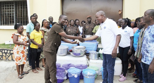 Assistant Superintendent of Prisons Courage Atsu (left), Volta Regional Chaplain of the Ghana Prisons Service, receiving the food items from Prophet Bright Brampah, General Overseer of Christ Power for All Nations Ministry, while some prison officers and members of the ministry look on 