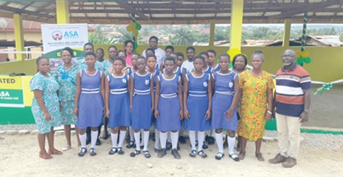 Rev. Happy Anyana (right), Headteacher of the Presbyterian New Town JHS, with some staff of the Asamankese Area of ASA Savings and Loans Limited and some pupils of the school