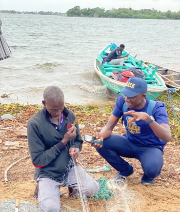 Daily Graphic's Timothy Ngnenbe interacting with Noah Aggrey as he mends his net at the shores of Azizape Island.