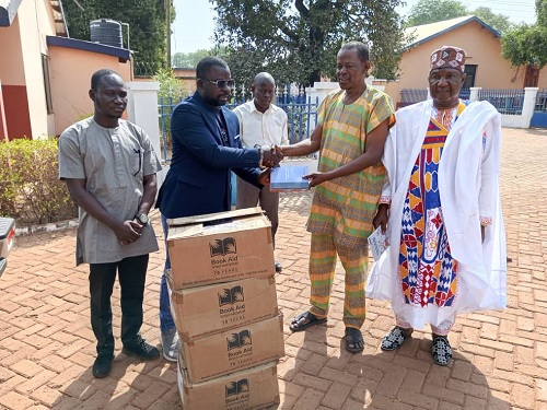 Amadu Zulyaden (2nd from left), Project Manager of School for Life, presenting some of the  books to Imoro Nuhu Alhassan (2nd from right),  Vice Principal of TACE