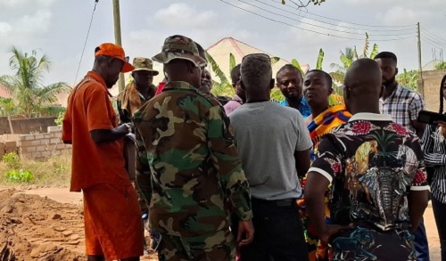 Obrimpong Dum (arrowed) addressing the indigenes at the site with military protection. INSET: The dish