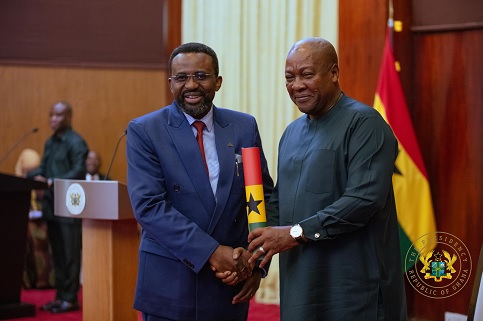 President Mahama (right) handing over the Scroll of Office to Dr Johnson Asiama, Governor of the Bank of Ghana, after swearing him in 