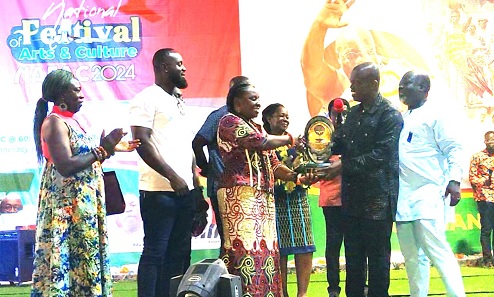 Nana Otuo Owoahene Acheampong (2nd from right), Executive Director of National Commission on Culture, presenting the NAFAC  2026 baton to Lydia Nyarko-Ampomah, Volta Regional Director of the  Centre for National Culture, at last year’s NAFAC in Techiman