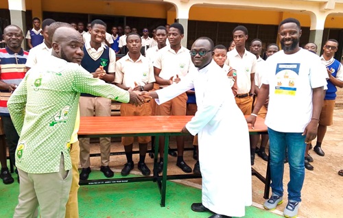  Moses Hinneh (left), a member of the Year Group, handing over the furniture to Rev. Fr Felix Taah (2nd from right), Rector of the school