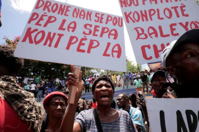 A woman holding a banner that reads in Haitian Creole “Drones are for the people, not against the people”, during a protest against insecurity, in Port-au-Prince, Haiti June 28, 2025. REUTERS/Jean Feguens Regala/File Photo Purchase Licensing Rights