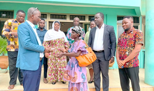 Eric Sey (left), Ga East Municipal Director of Education, presenting a cash donation to Gloria Owusu Boateng (right), sister of the crush victim